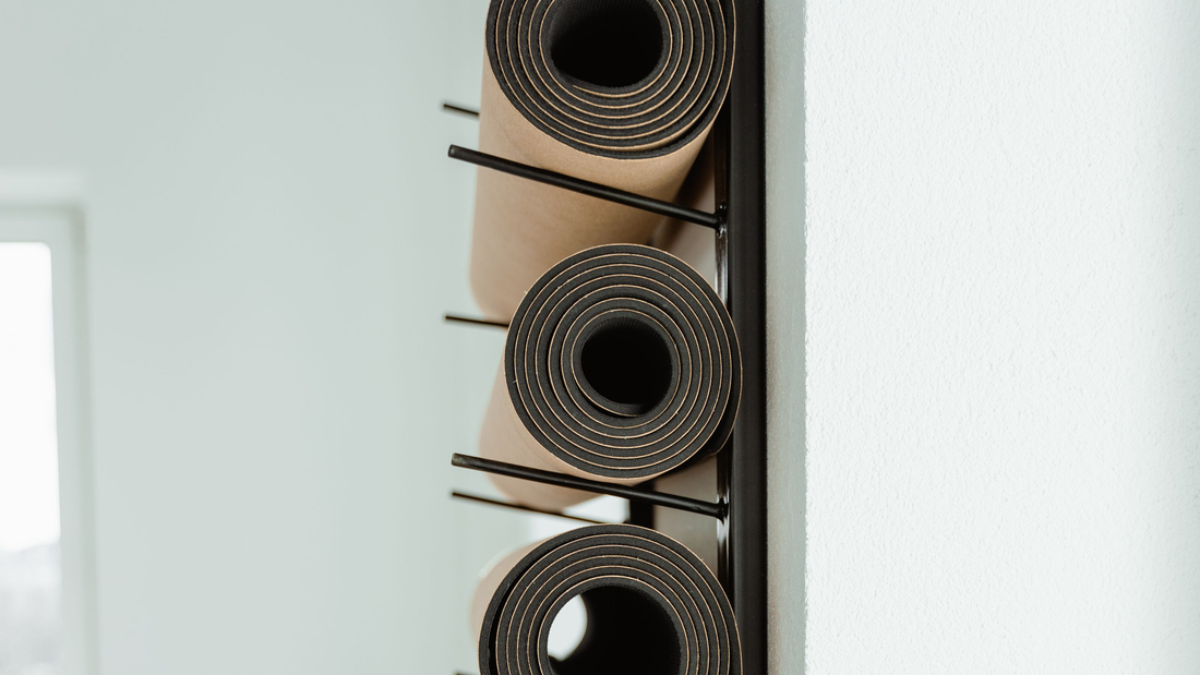 Aufgerollte Trainingsmatten in einem Wandhalter in einem hellen Studio
